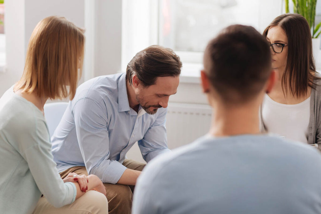 Man in an outpatient addiction treatment program talks to his peers