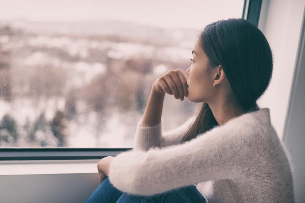Woman looks out the window of depression recovery centers